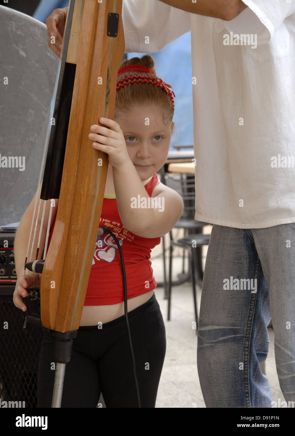 Einem jungen kubanischen Mädchen Unterstützung ihres Vaters ein elektrischer Stand-up Bass zu spielen Stockfoto