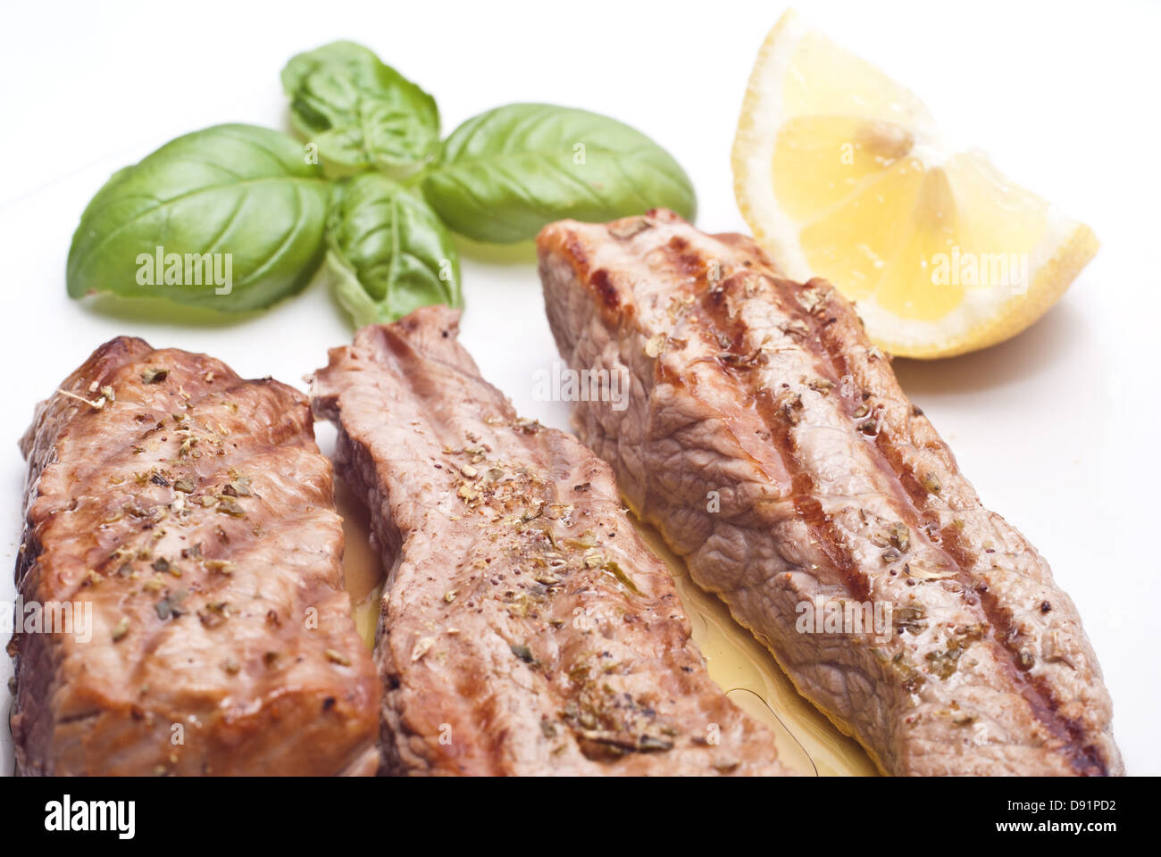 Gegrilltes Rindfleisch mit Basilikum und Zitronen in Scheiben geschnitten Stockfoto