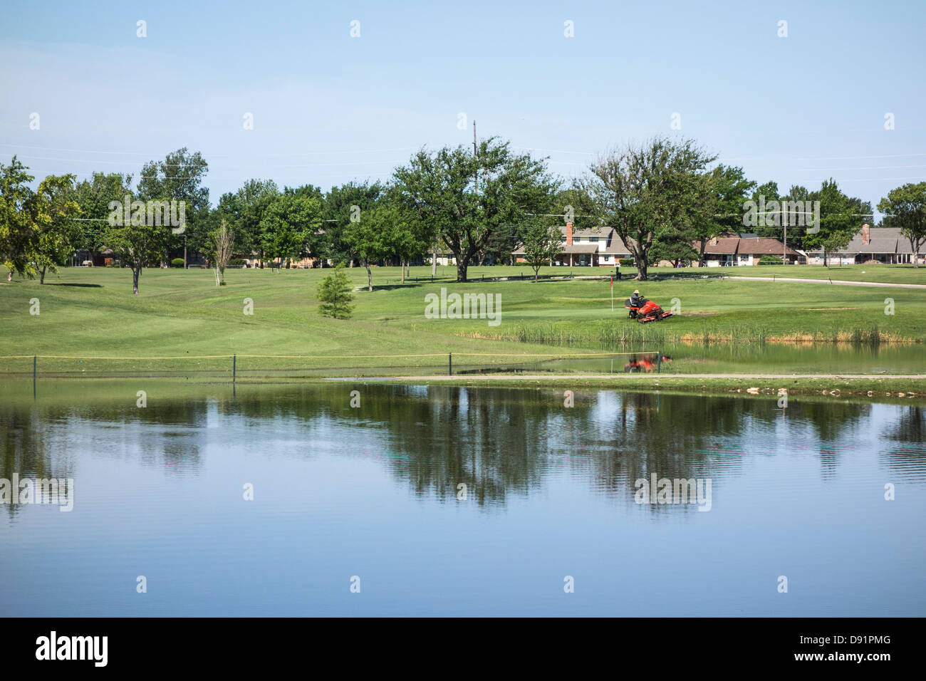 Ein groundskeeper mäht Gras in der Nähe von einem Grün auf Lake Hefner Golf Course in Oklahoma City, Oklahoma. Stockfoto