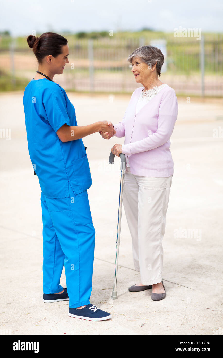 junge Krankenschwester in uniform im Gespräch mit älteren Frau im freien Stockfoto