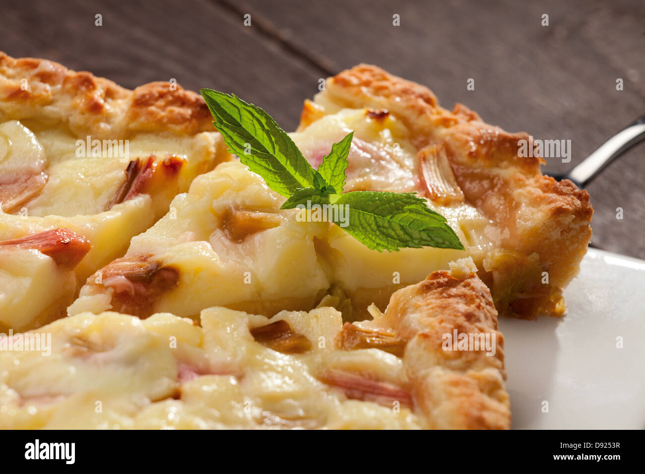 Stück Torte mit Rhabarber und Pudding, frische grüne Minze Stockfoto