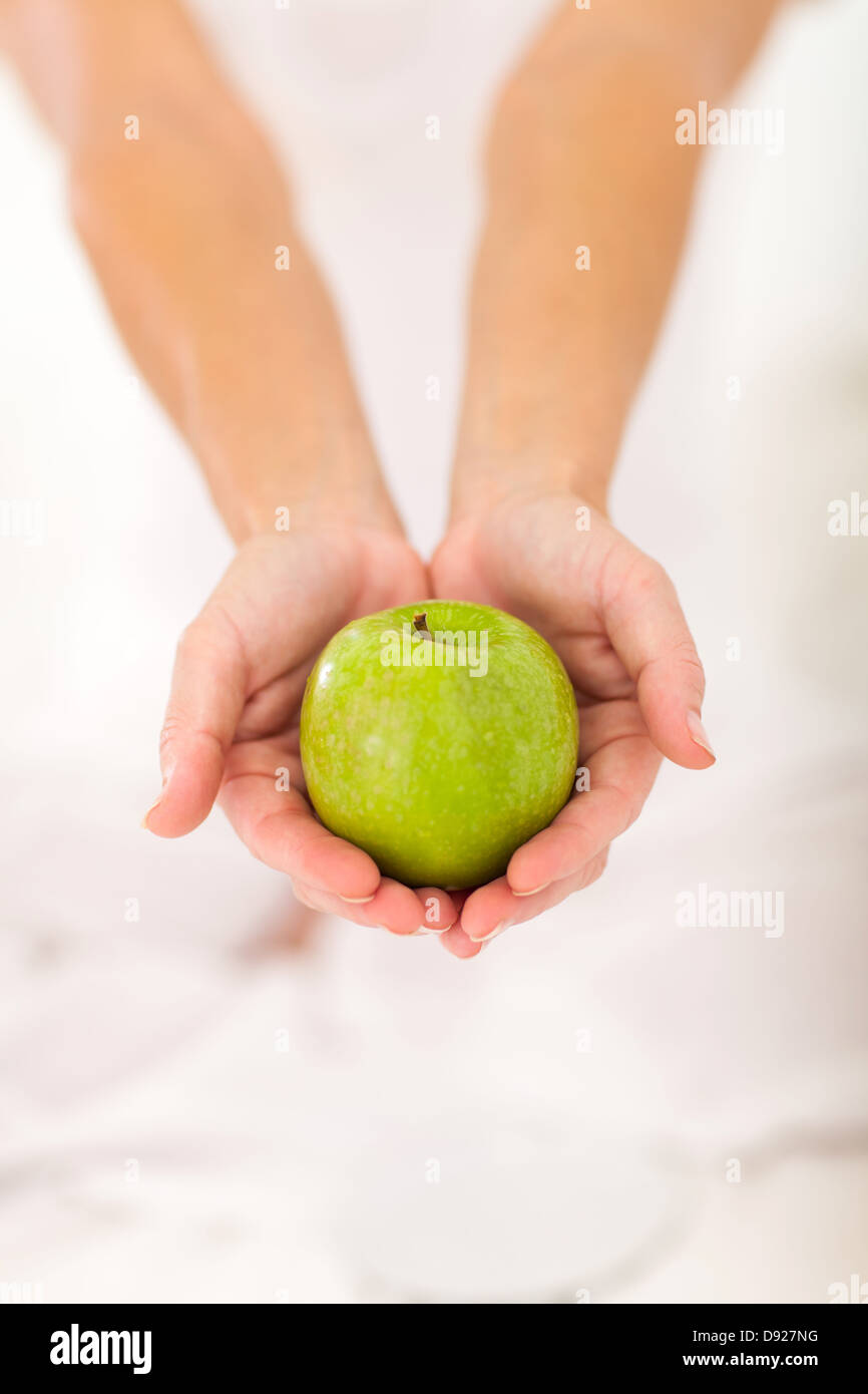 Frau mit grünem Apfel mit beiden Händen Stockfoto