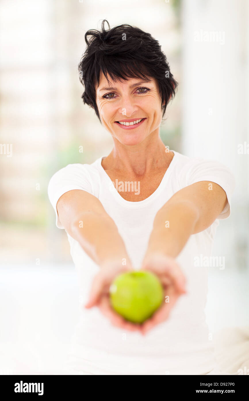sehr reife Frau hält einen Apfel mit beiden Händen Stockfoto
