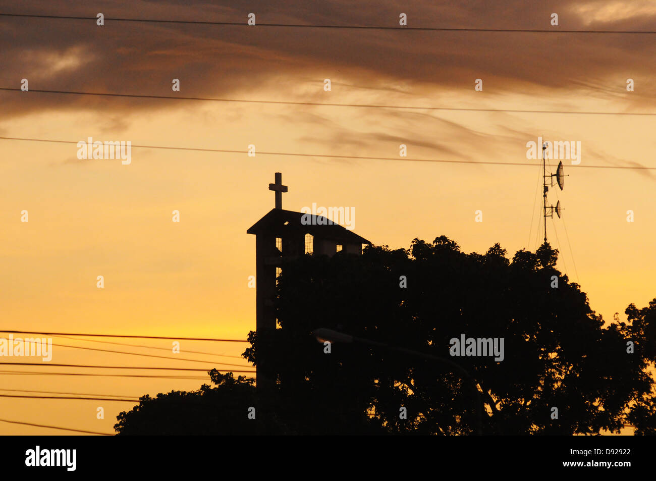 Eine Kirche mit einem konkreten Kreuz auf den Sonnenuntergang. Roxas, Insel Mindoro, Philippinen Stockfoto