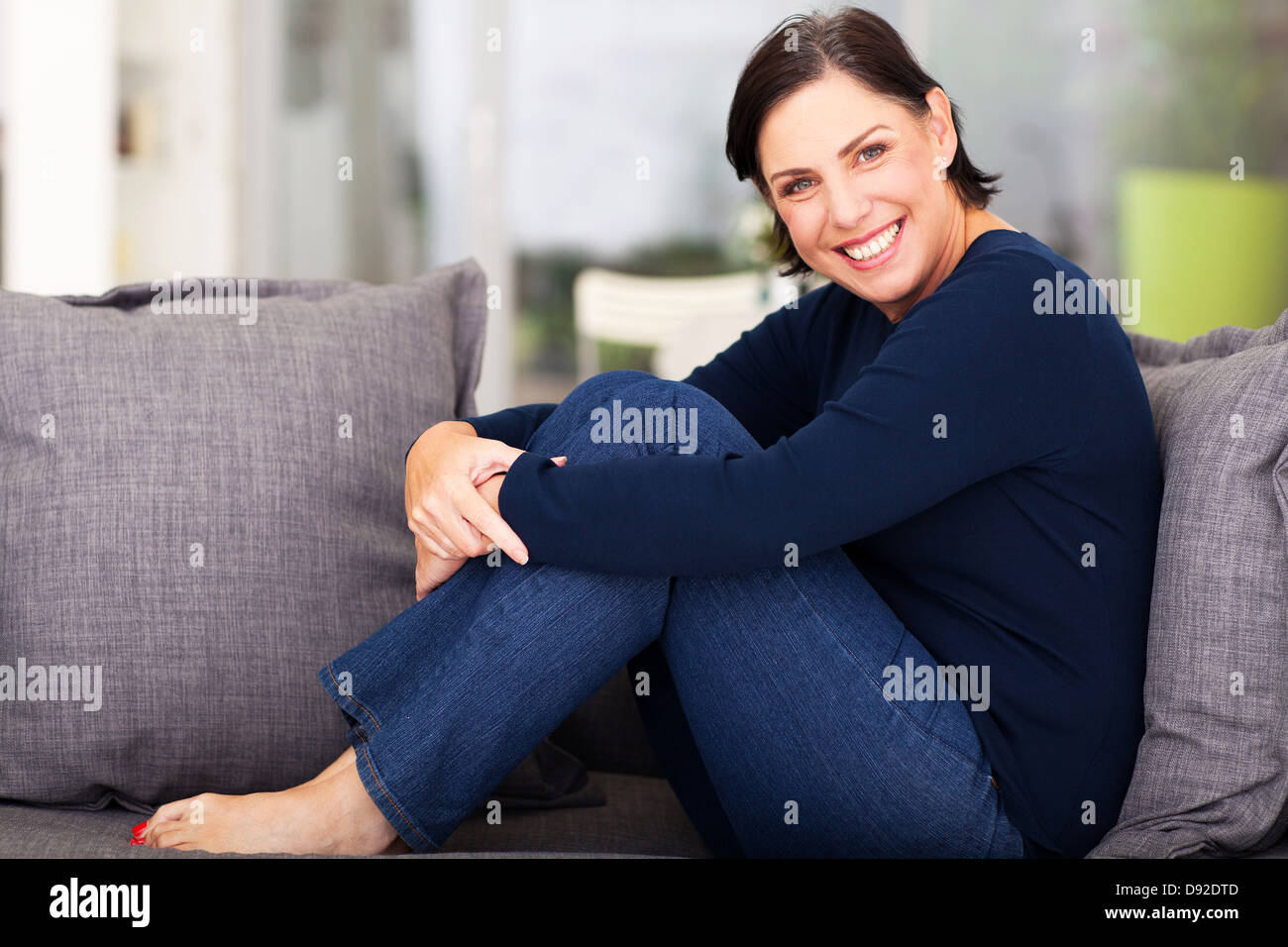 fröhliche mittlere gealterte Frau entspannen auf dem sofa Stockfoto
