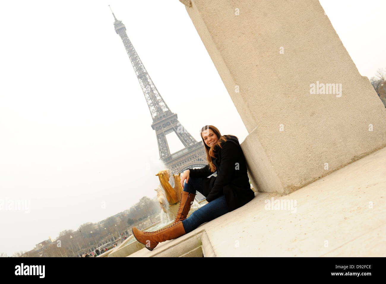 Junge Frau sitzt in der Nähe von Eiffelturm Paris Frankreich Stockfoto