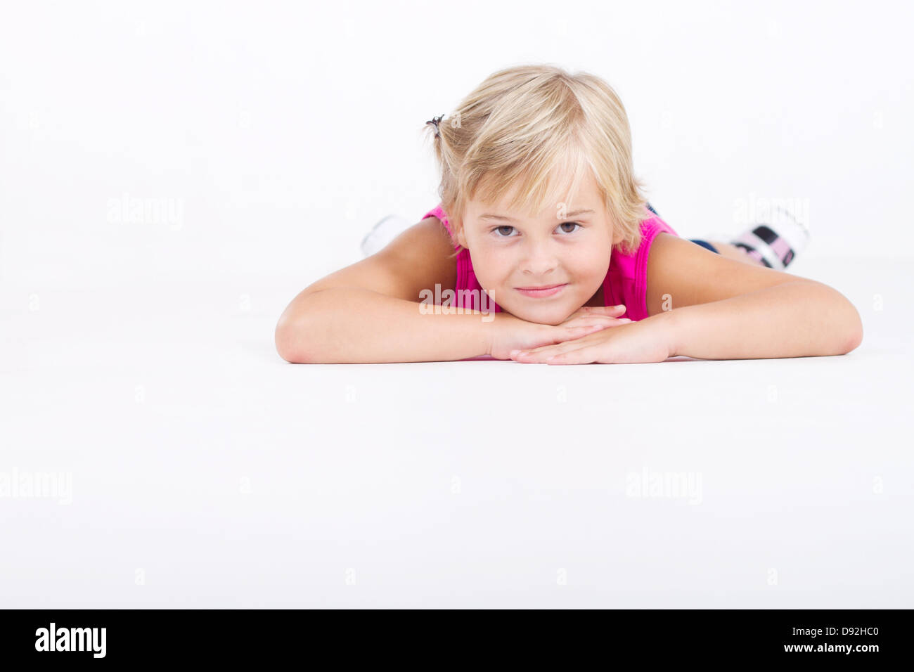 niedliche kleine Mädchen auf Boden liegend, isoliert auf weiss Stockfoto