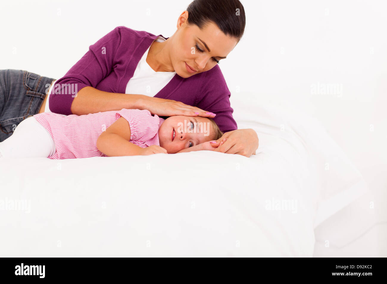 fürsorgliche Mutter tröstete weinende Babymädchen auf Bett Stockfoto