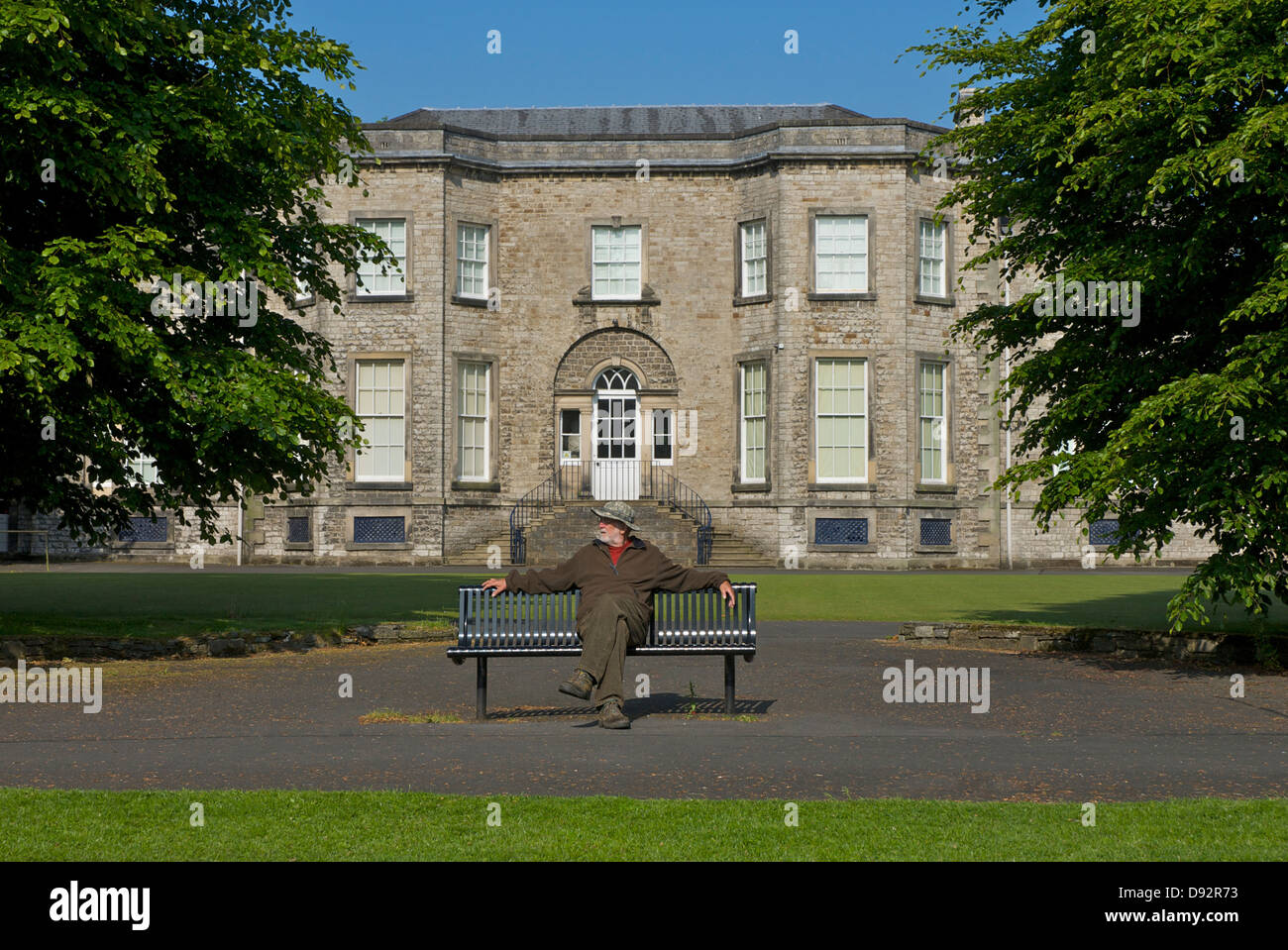 Senior-Mann sitzt auf einer Bank vor der Abbot Hall Art Gallery, Kendal, Cumbria, England, Großbritannien Stockfoto