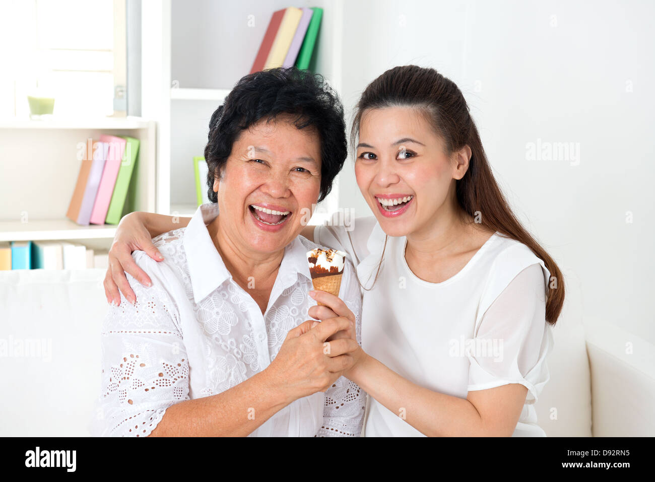 Teilen ein Eis essen. Asiatische Familienglück zu Hause Essen teilen. Schöne ältere Mutter und Erwachsene Tochter Essen Dessert zusammen. Stockfoto