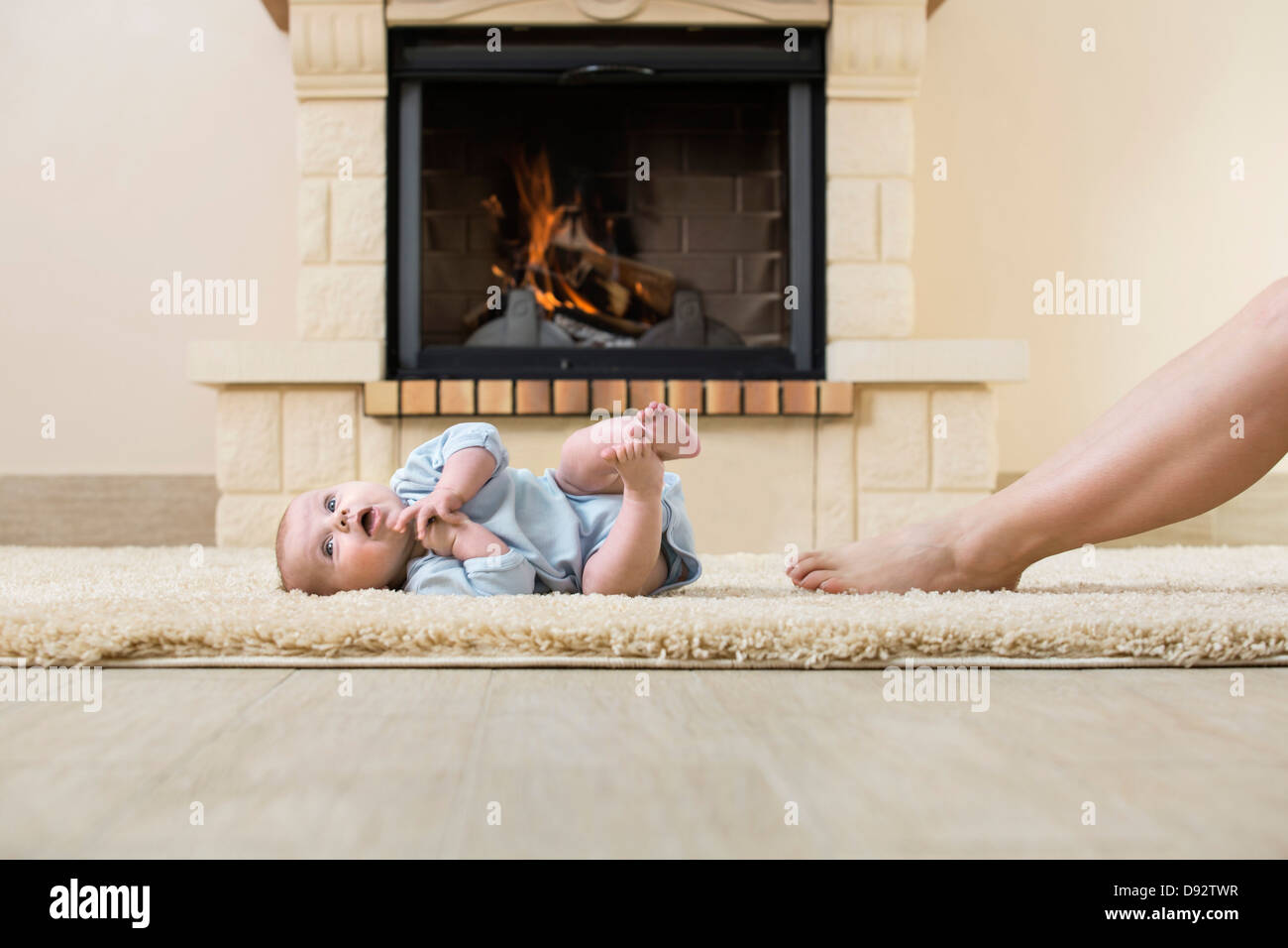 Baby und Mutter Bein auf Teppich vor Feuer Stockfoto