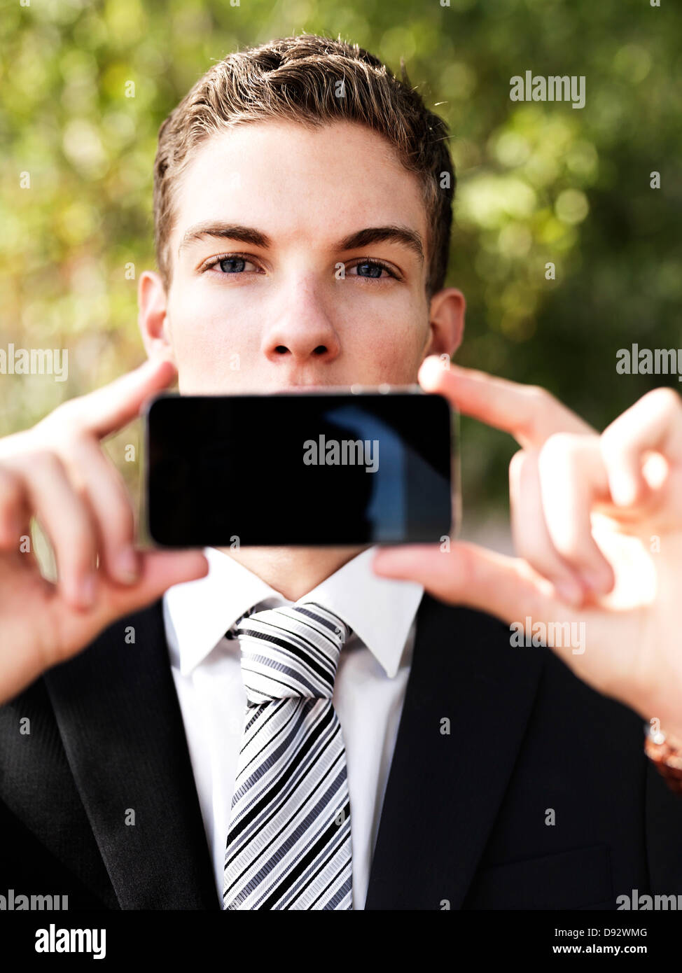 Ein junger Geschäftsmann sein Smartphone vor den Mund halten Stockfoto