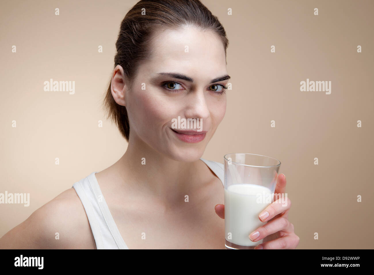 Eine lächelnde junge Frau mit einem Glas Milch Stockfoto