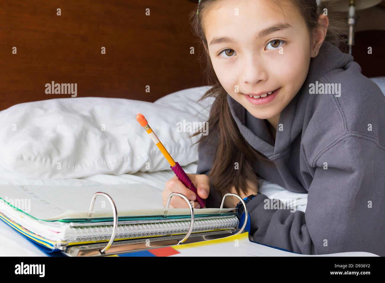Gemischte Rassen Mädchen Hausaufgaben auf Bett Stockfoto