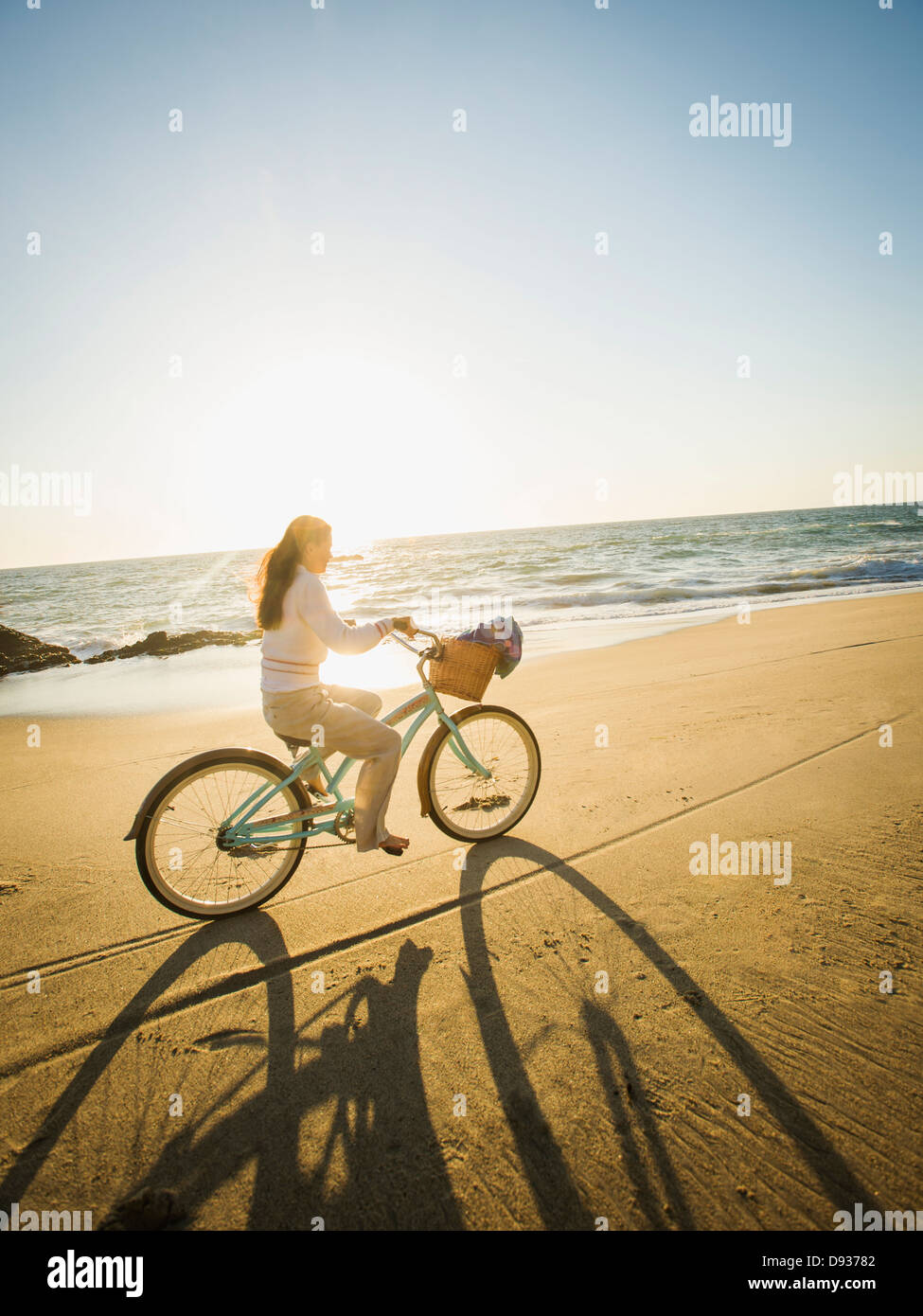 Gemischte Rassen Frau Reiten Fahrrad am Strand Stockfoto