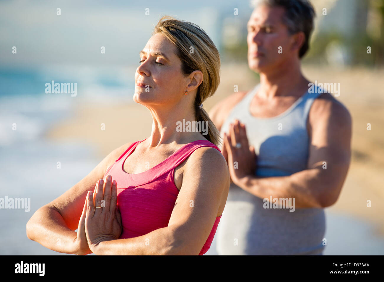 Kaukasische paar meditieren am Strand Stockfoto