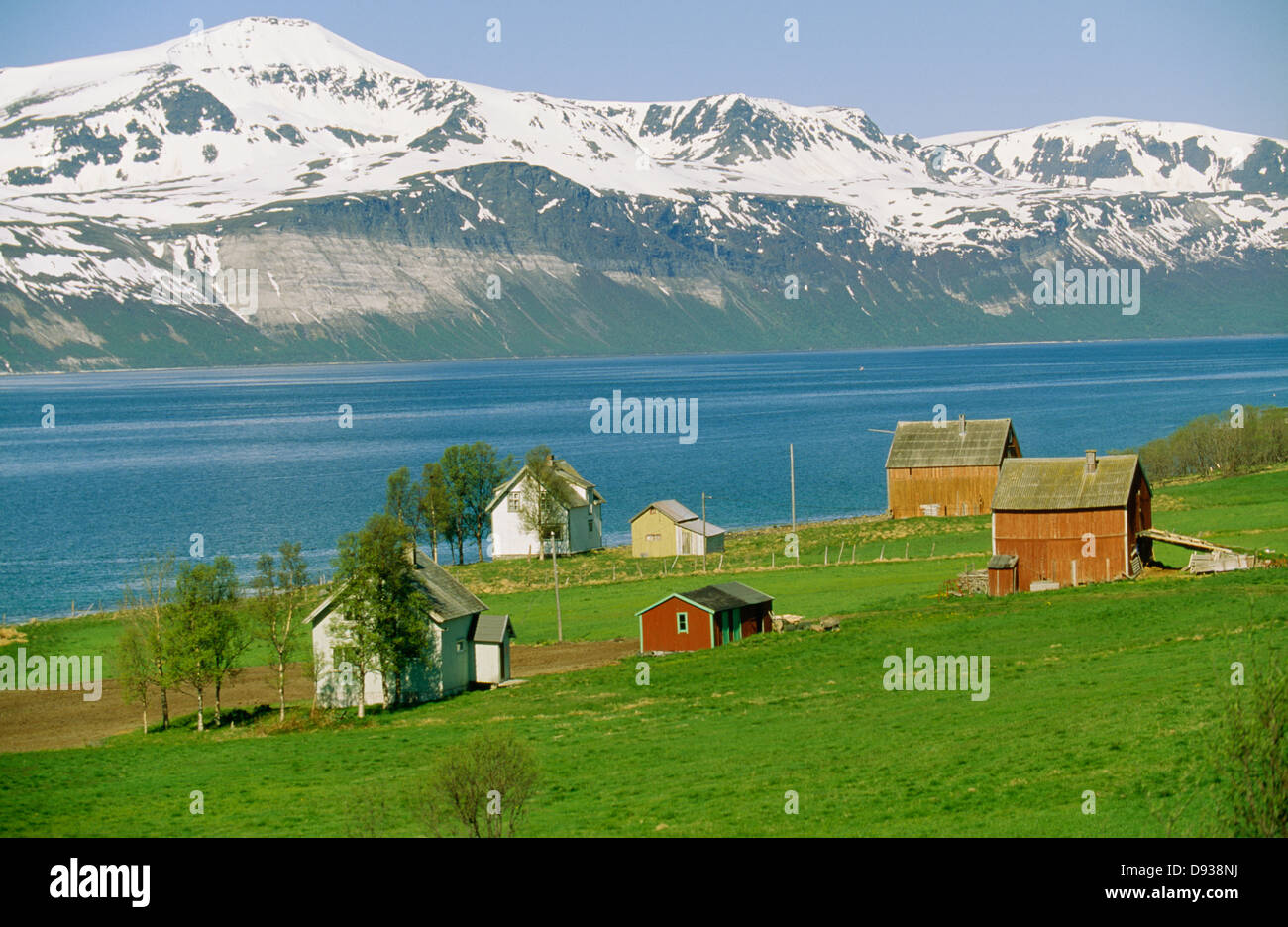 Fjord, vorbei an schneebedeckten Berge und Häuser Stockfoto