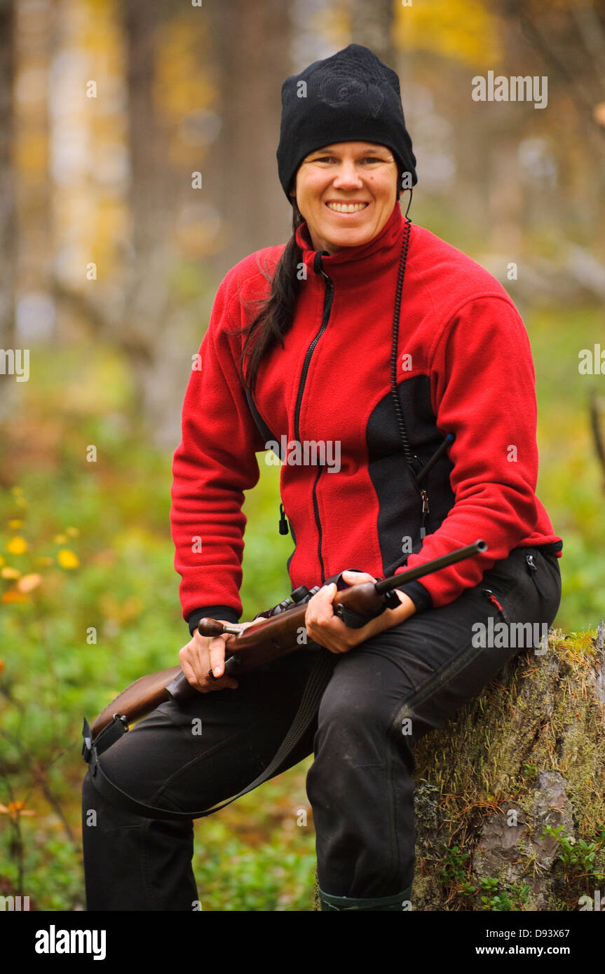 Mitte Erwachsene Frau Holding Gewehr im Wald Porträt Stockfoto