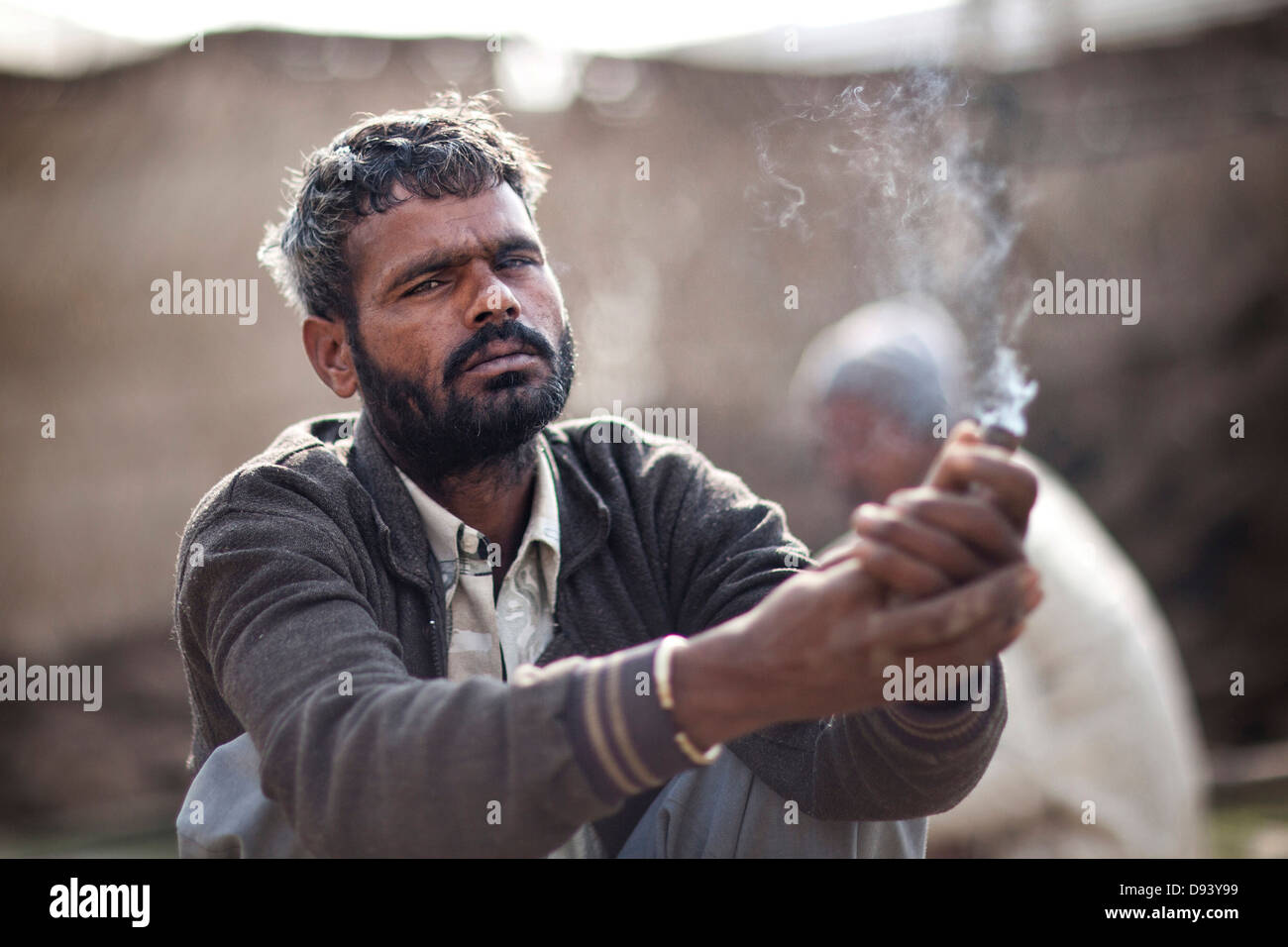 Porträt eines lokalen Dorfbewohners raucht eine Pfeife auf der Kumbh Mela 2013 in Allahabad, Indien Stockfoto