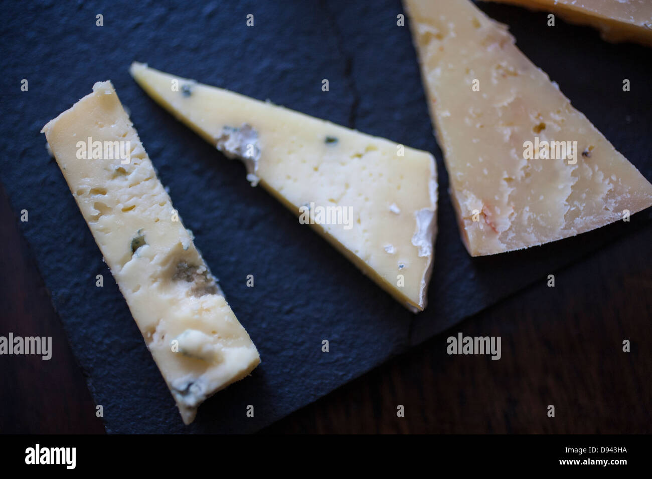 Käse Verkostung Proben auf schwarzem Schiefer Cheddar blau gouda Stockfoto