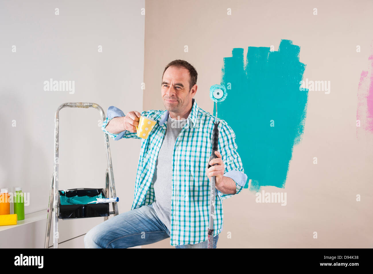 Reifer Mann mit Kaffeepause von Renovierung seiner Wohnung durch Streichen der Wände Stockfoto