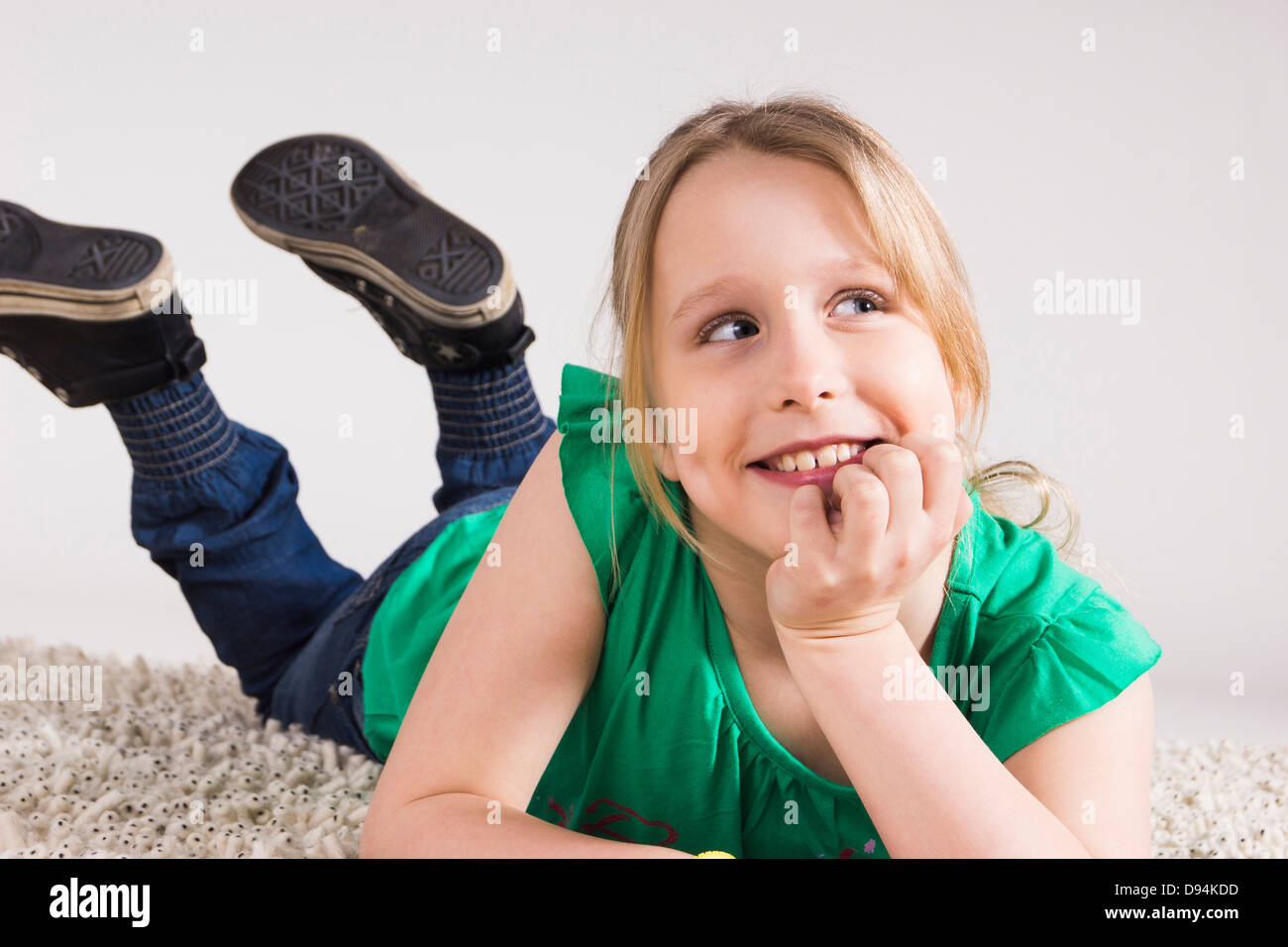 Porträt eines Mädchens auf Seite gelehnt und liegend auf Bauch im Studio Stockfoto