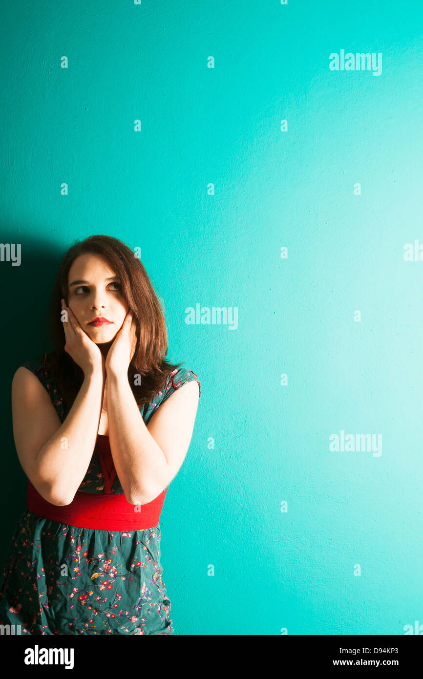 Junge Frau lehnt sich an die Wand im Studio Stockfoto