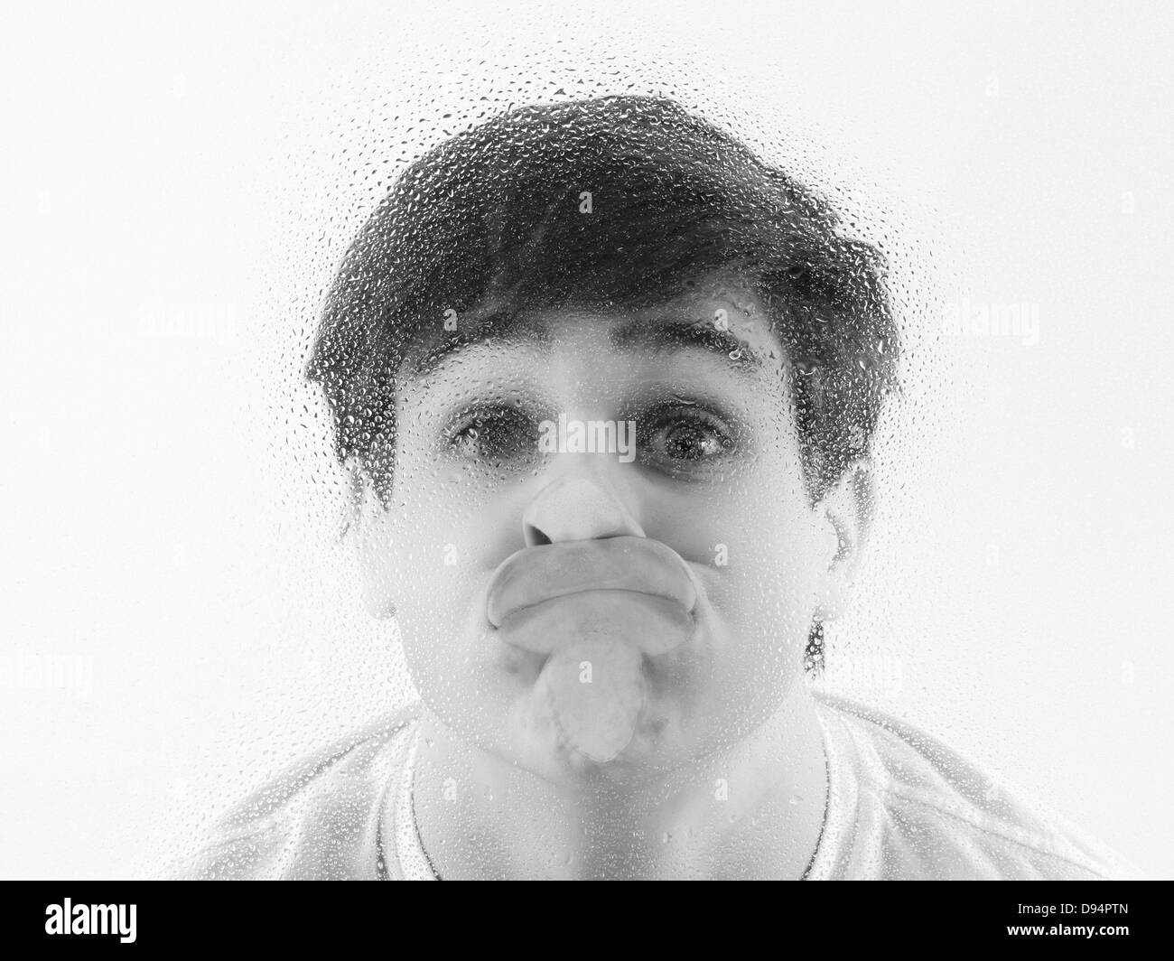 Nahaufnahme eines Teenagers mit Gesicht drückte gegen nasse Glas Stockfoto