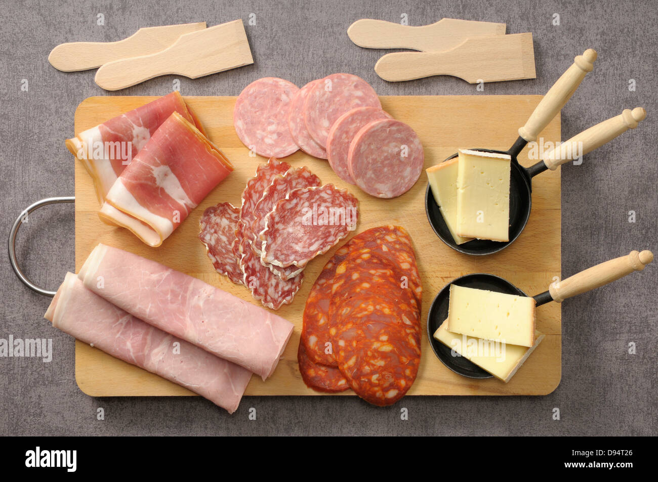 Draufsicht von Wurst und Käse für Raclette auf Schneidebrett auf grauem Hintergrund, Studioaufnahme Stockfoto