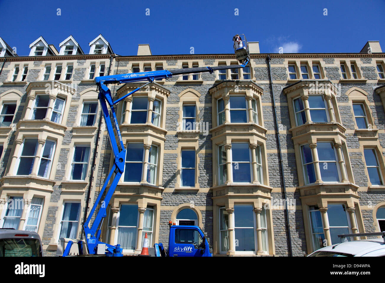 Hubarbeitsbühne LKW oder hab bei der Arbeit an einem Gebäude direkt an der Strandpromenade in Aberystwyth an der Westküste von Wales Stockfoto