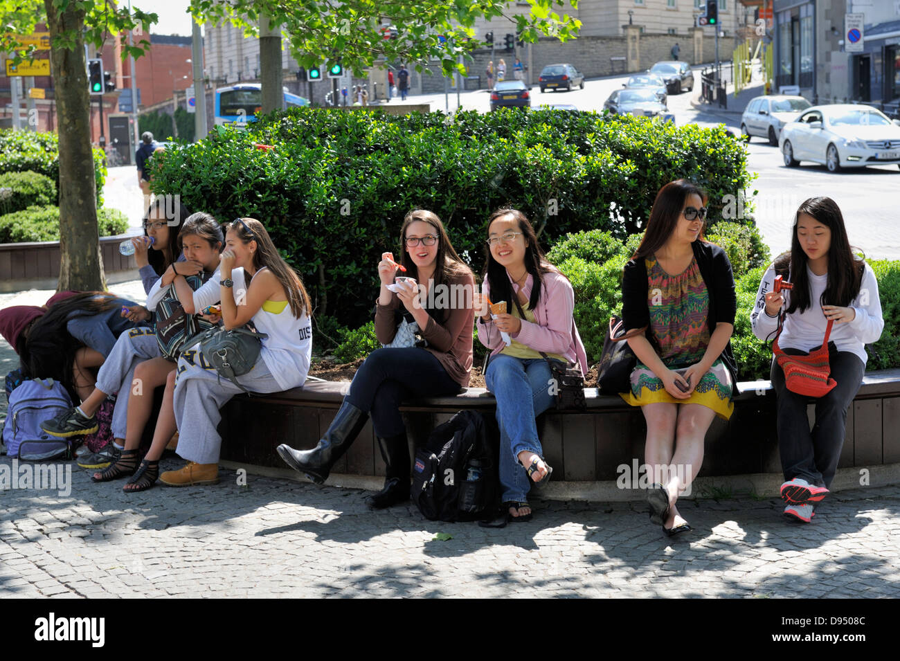 Junge Frauen sitzen auf Bank in Bristol City Centre-Promenade Stockfoto