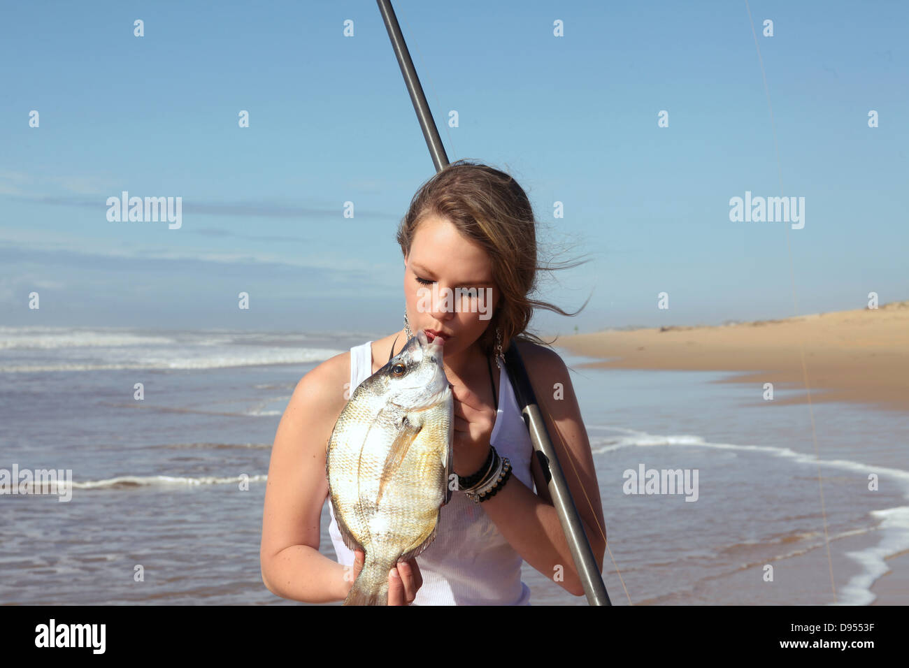 eine schöne blonde Fisher-Dame ist ein Fisch küssen, die sie gerade gefangen Stockfoto