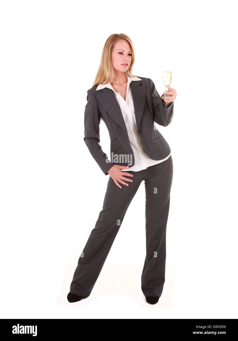Eine schöne junge blonde Geschäftsfrau hält ein Glas Champagner. Sie ist in einem grauen Suite und Jacke gekleidet. Stockfoto