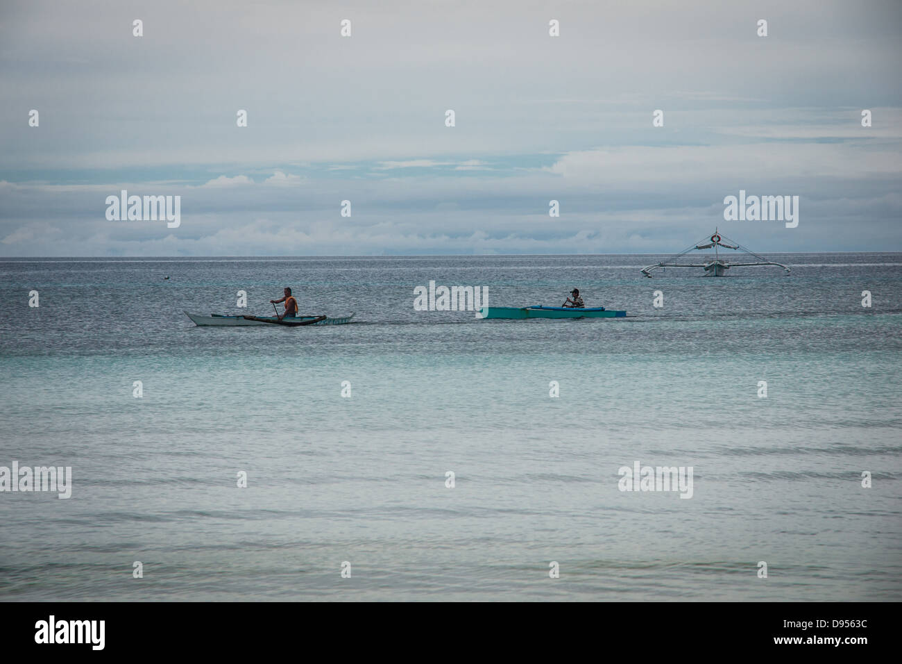 Zwei Filipinos paddeln entfernt im traditionellen Auslegerboote auf Dumaluan Beach auf der Insel Bohol in Central Visayas, Philippinen Stockfoto