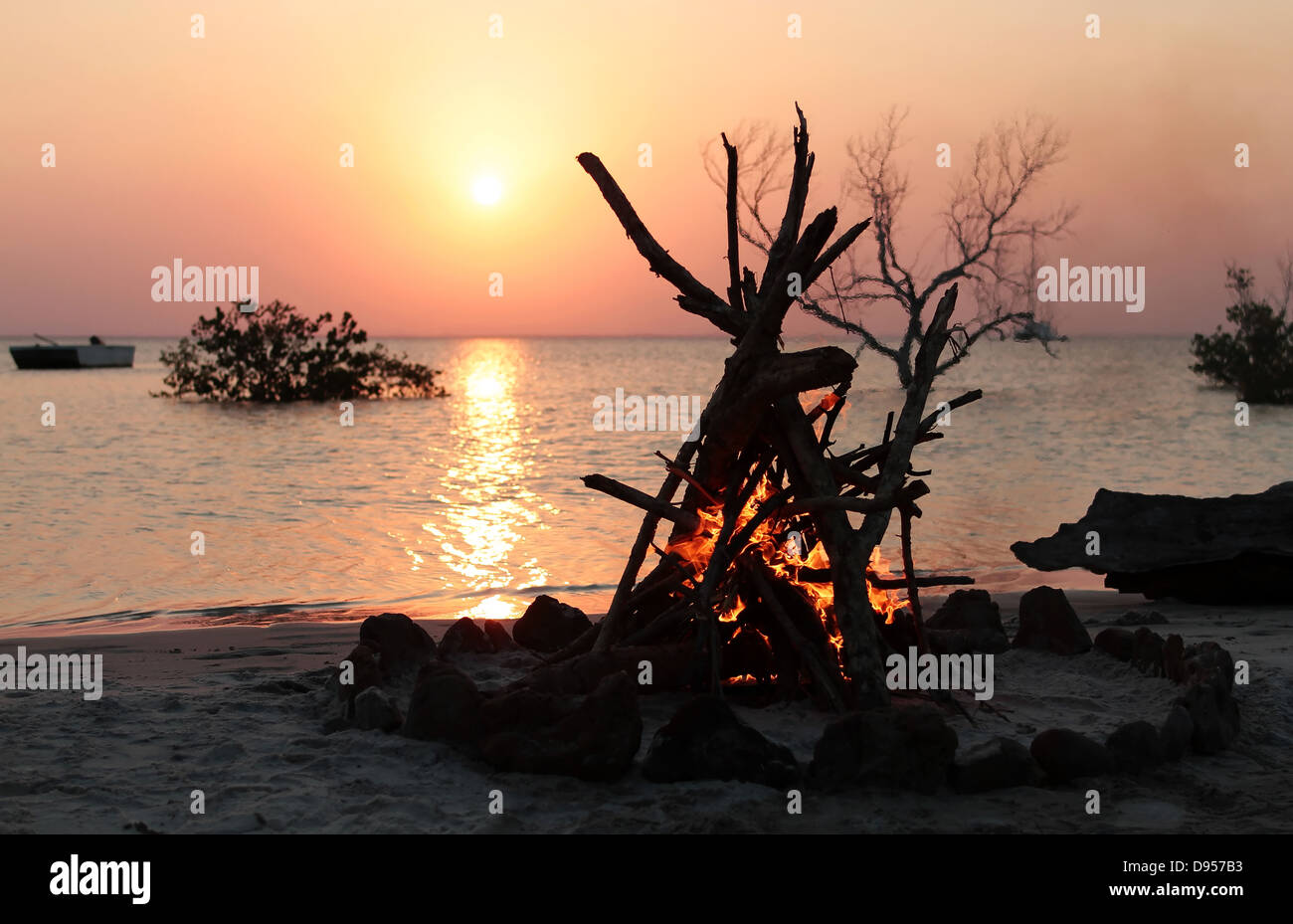Ein schönes Lagerfeuer an einem tropischen Strand bei Sonnenuntergang Stockfoto