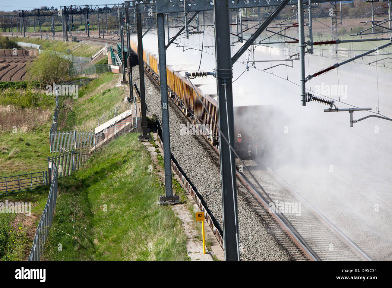 Eine Ladung Sand weht von der Rückseite eines Güterzuges auf der West Coast Main Line. Stockfoto