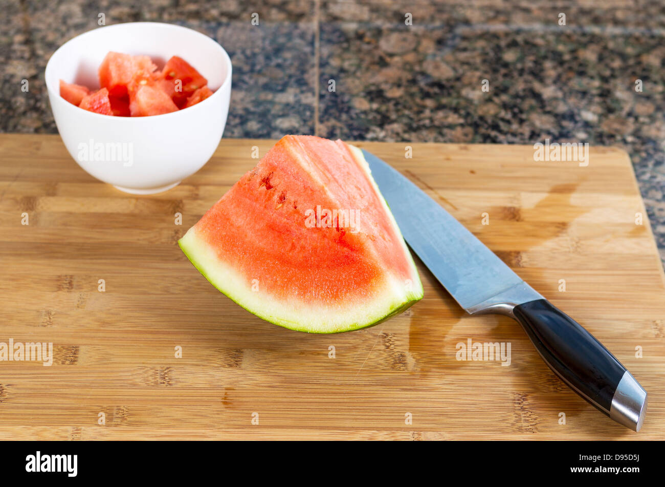 in Scheiben geschnittenen Wassermelone mit Schneidmesser, Schüssel und Holzbrett Stockfoto