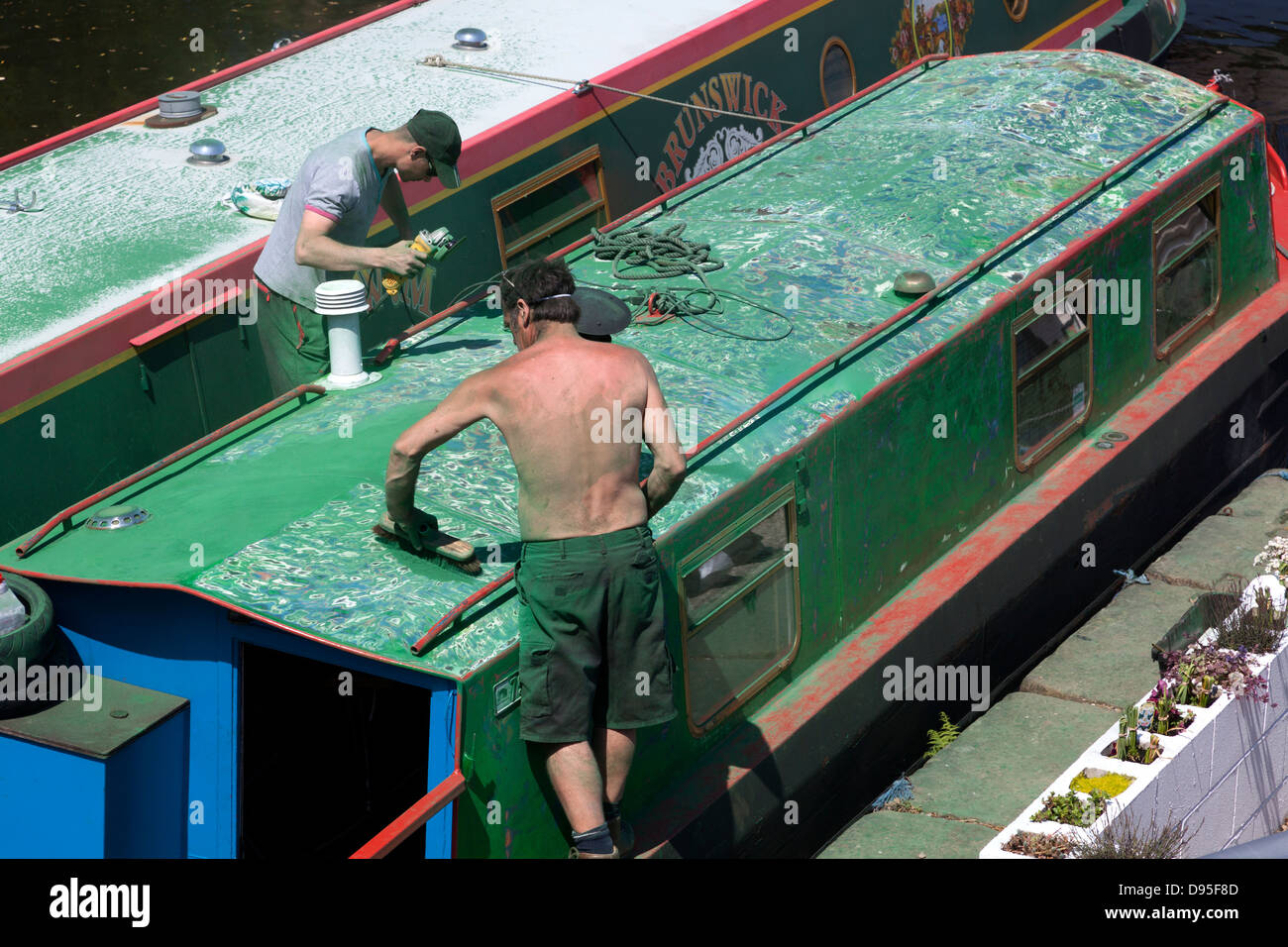 Männer Abisolieren der Farbe von einem Narrowboat im Aspley Becken, Huddersfield, West Yorkshire Stockfoto