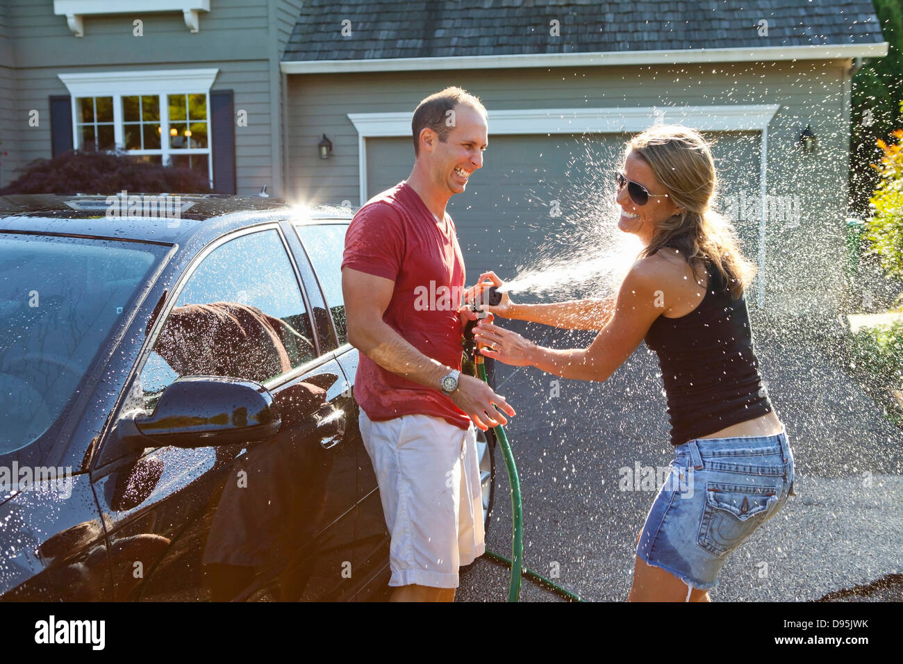 Paar, waschen ihr Auto in der Einfahrt ihres Hauses an einem sonnigen Sommernachmittag in Portland, Oregon, USA Stockfoto