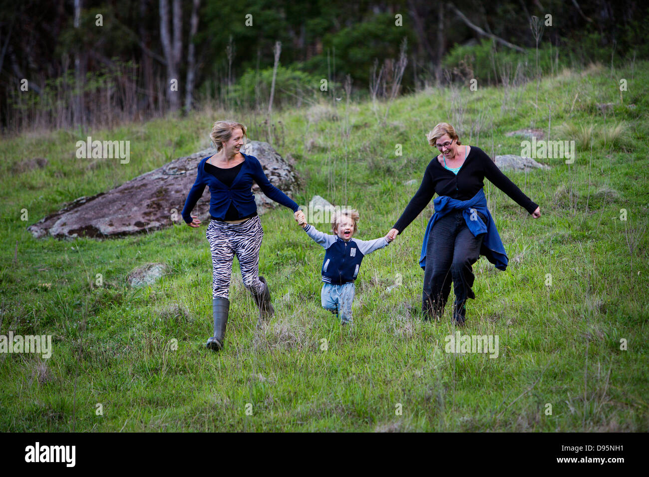 Familie Gruppe von Mutter, Tochter und Enkel laufen bergab Hand in Hand und lachen Stockfoto