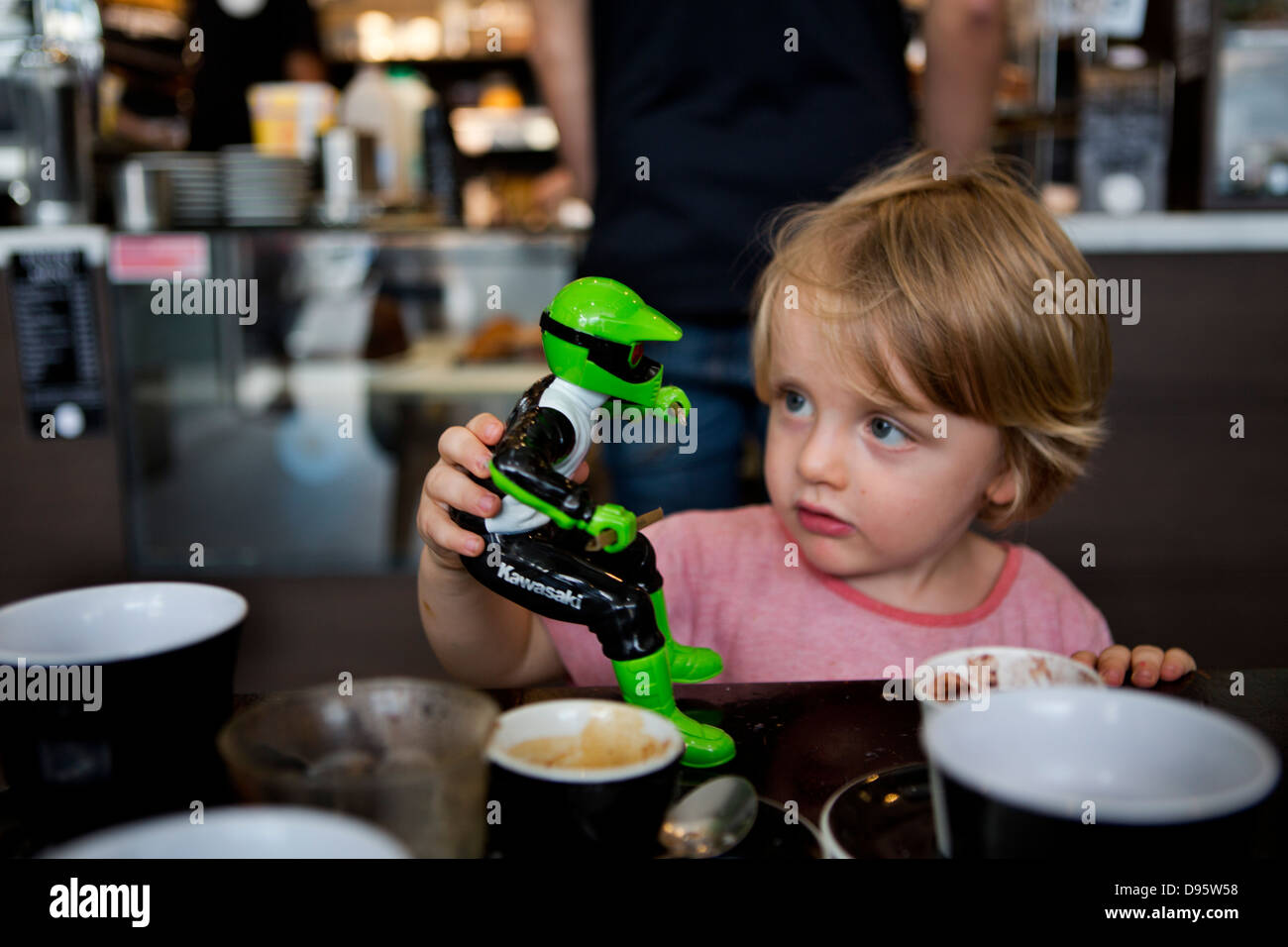 3 jährige Junge spielt mit grüne Aktion Figur auf Tisch Stockfoto