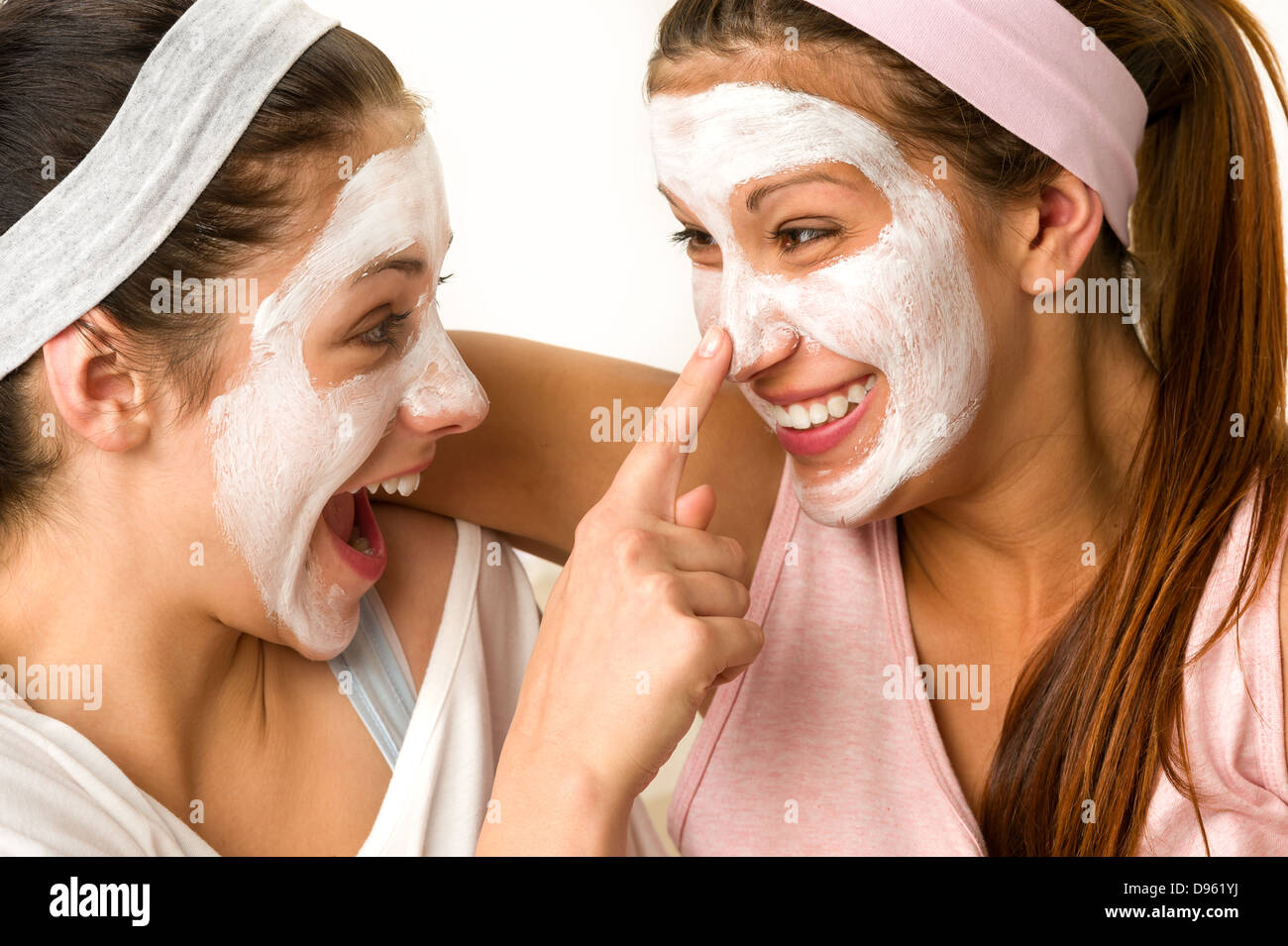 Verspielte Teen tragen Maske berührt ihre Freundin Nase Stockfoto