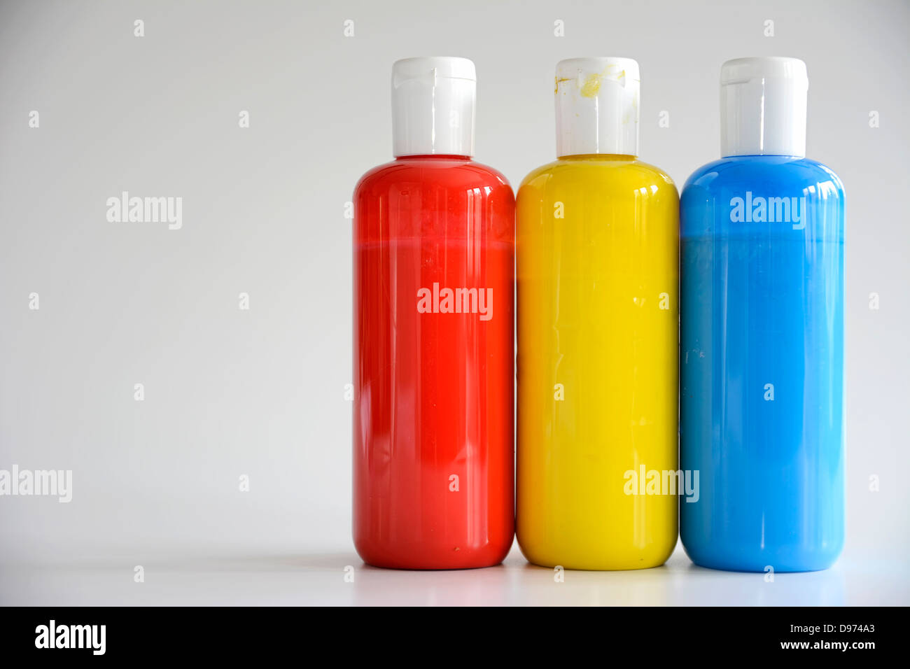 Rot, gelb, blau Flaschen auf grauem Hintergrund Stockfoto
