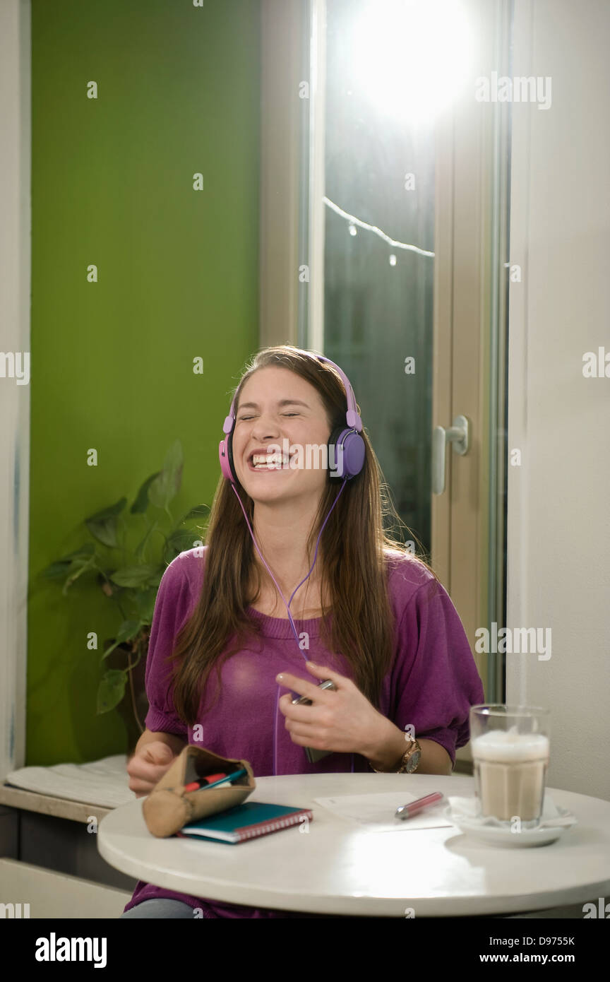Deutschland, Bayern, München, junge Frau hören von Musik im Café, Lächeln Stockfoto