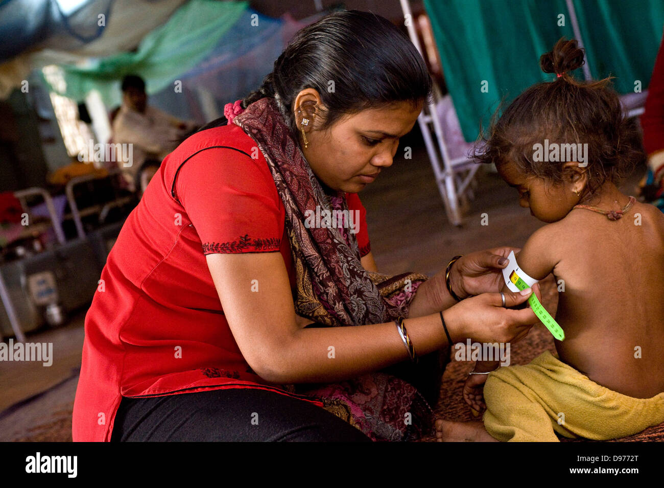 Die Gesundheit der Arbeitnehmer prüft den Oberarm-Umfang dieses junge Kind in Indien mit einem Schnelltest – um sicherzustellen, dass Sie Stockfoto