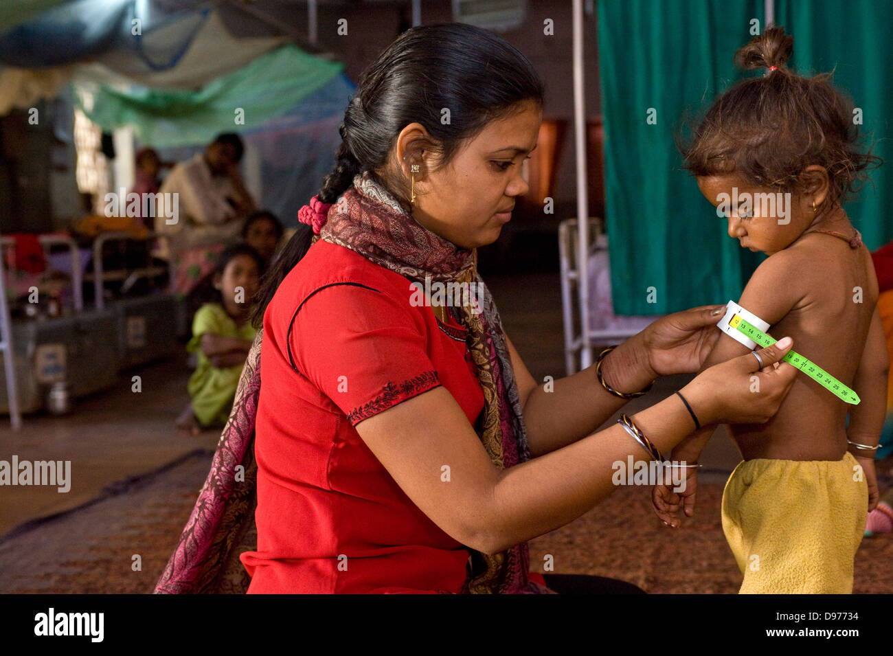 Die Gesundheit der Arbeitnehmer prüft den Oberarm-Umfang dieses junge Kind in Indien mit einem Schnelltest – um sicherzustellen, dass Sie Stockfoto