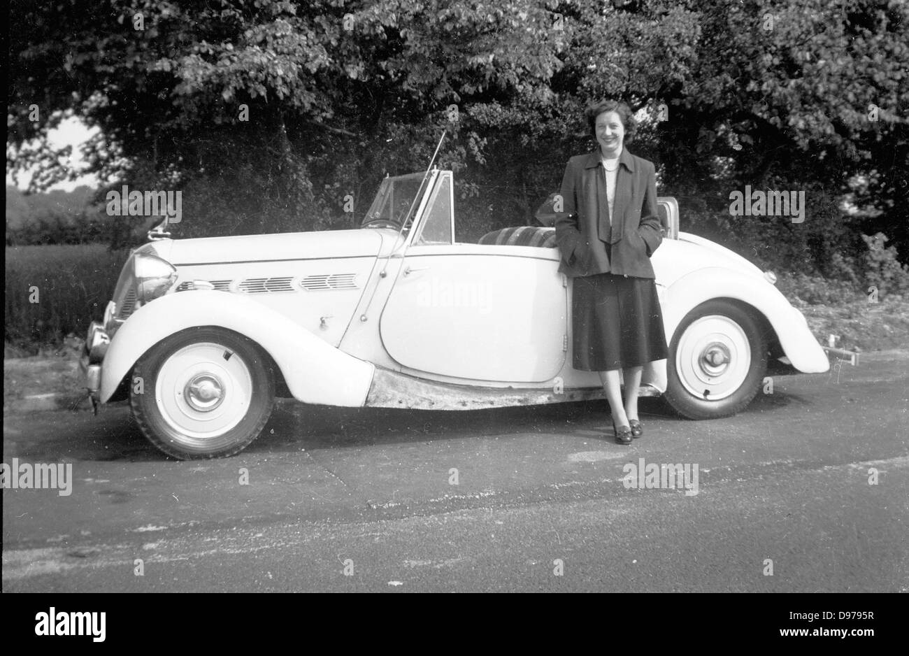Historisches Bild von der 1950er Jahre. Ländlichen England und Frau posiert stolz für ein Bild mit ihrem Cabrio-Sportwagen am Straßenrand. Stockfoto