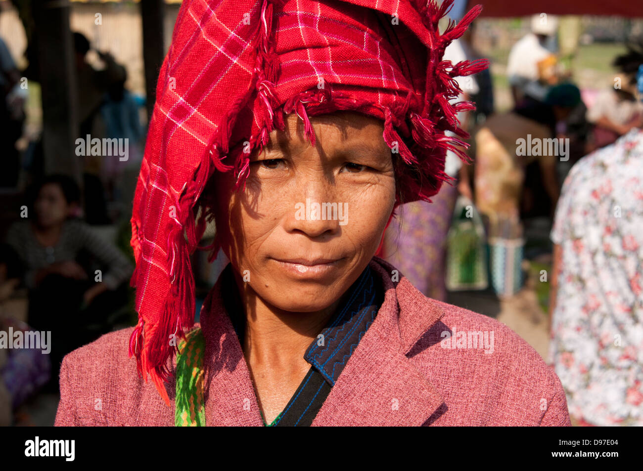 PA-O Frau trägt einen roten aufgegebenen Kopfschmuck, schaut in die Kamera in einem Markt, Myanmar (Burma) Stockfoto