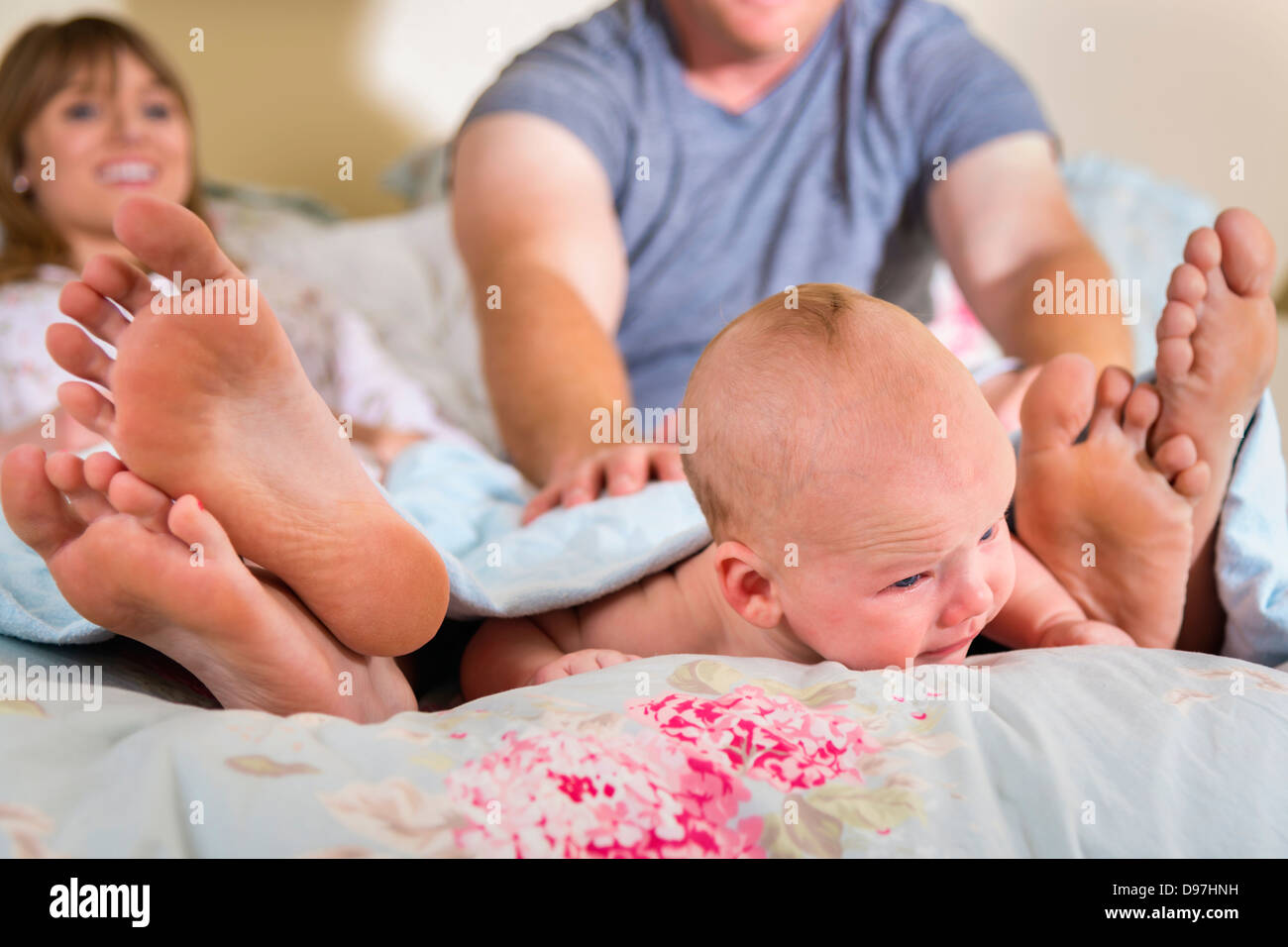 Junge Eltern mit ihrem Baby im Bett spielen Stockfoto