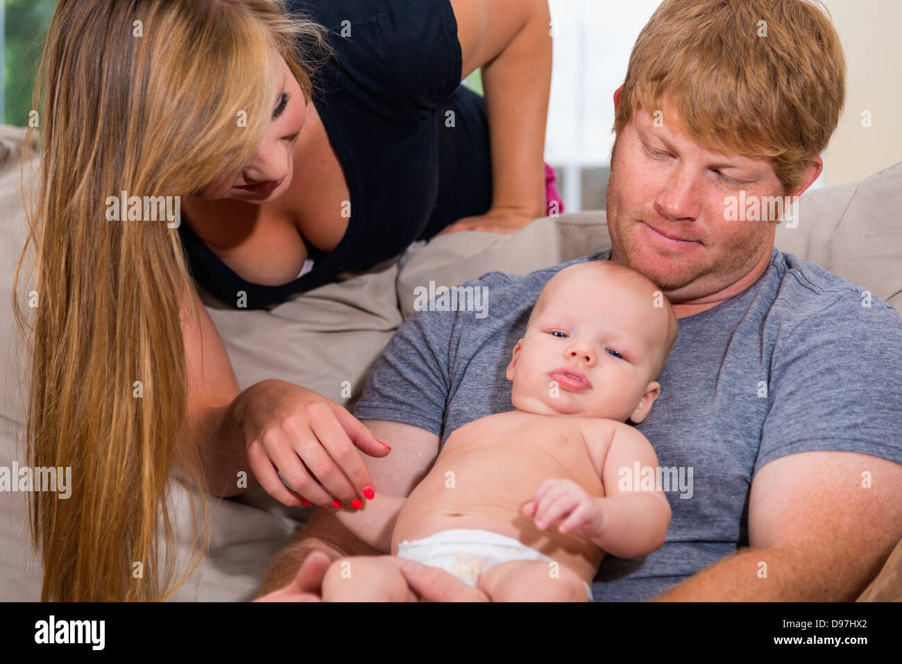 Junge Eltern mit ihrem Baby auf dem Sofa für ihr Wohnzimmer Stockfoto